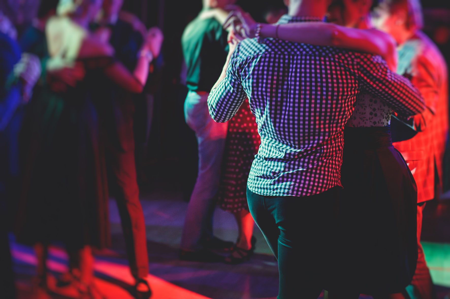 Couples dancing traditional latin argentinian dance milonga in the ballroom, tango salsa bachata kizomba lesson in the red lights, dance festival